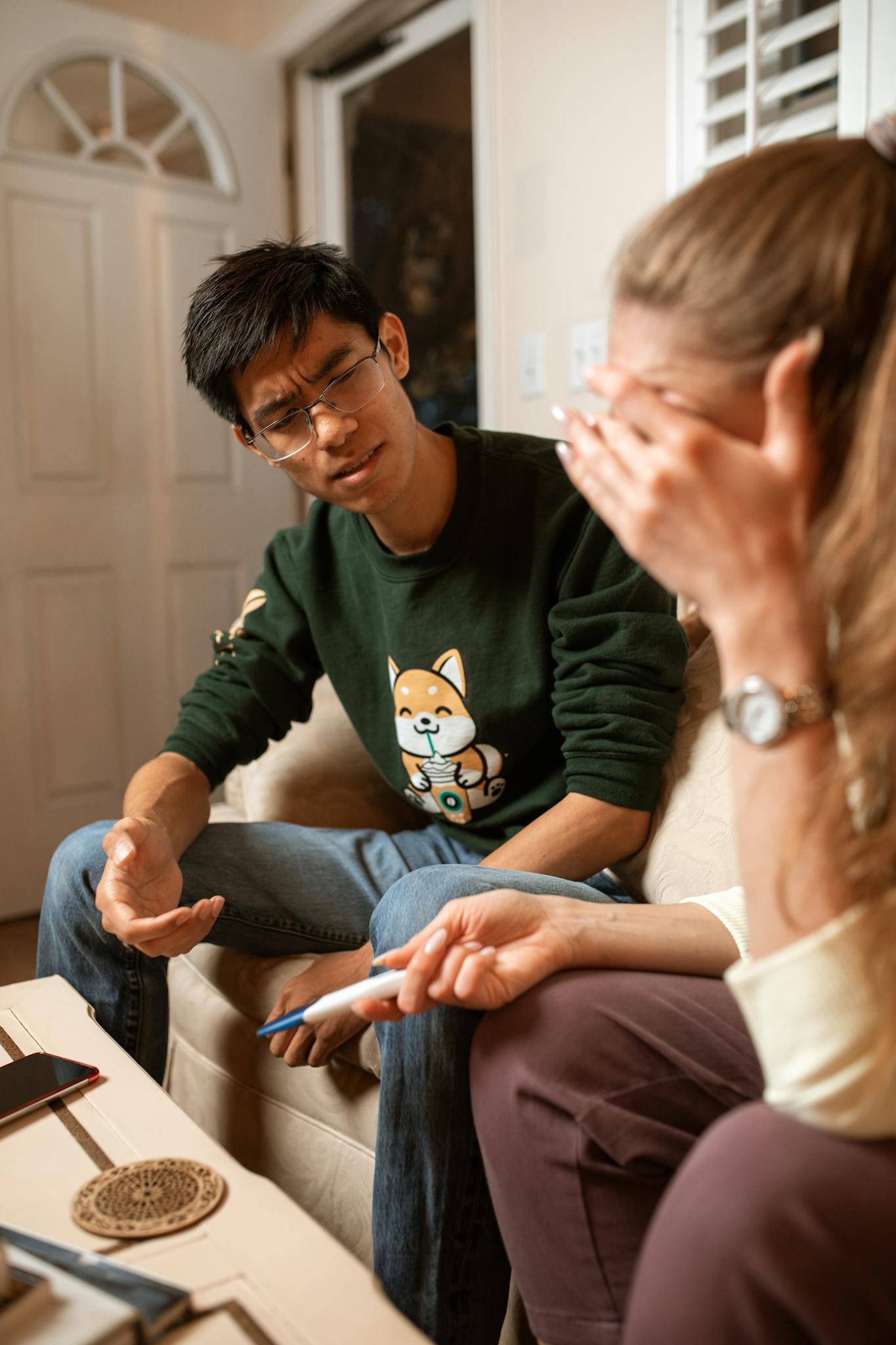 A couple sitting indoors, emotionally reacting to a pregnancy test result.